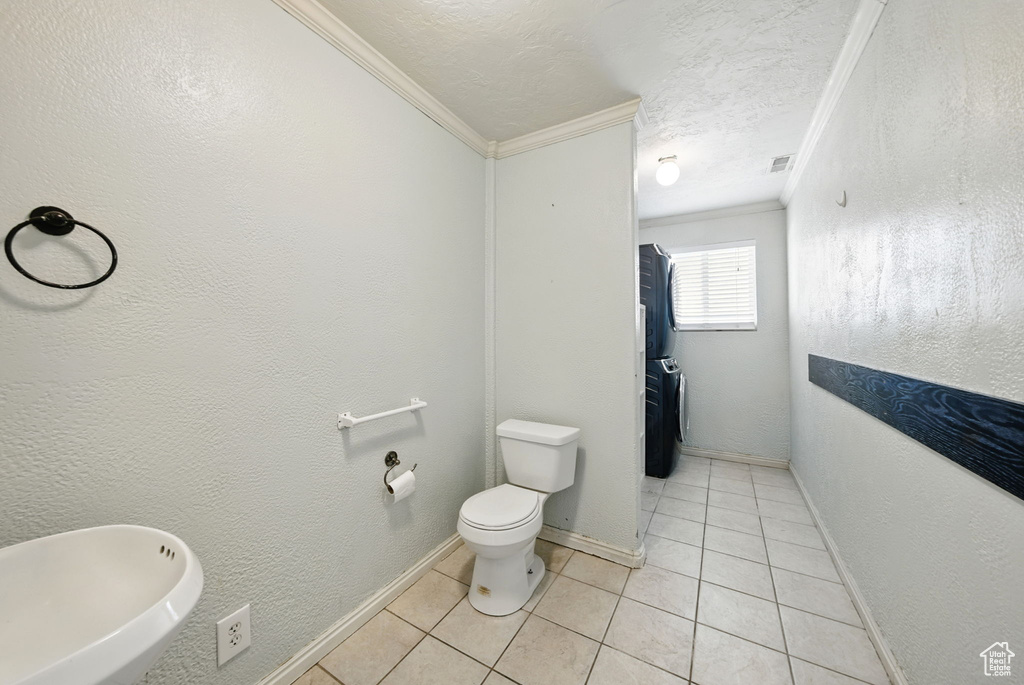 Bathroom with ornamental molding, tile patterned floors, toilet, and baseboards
