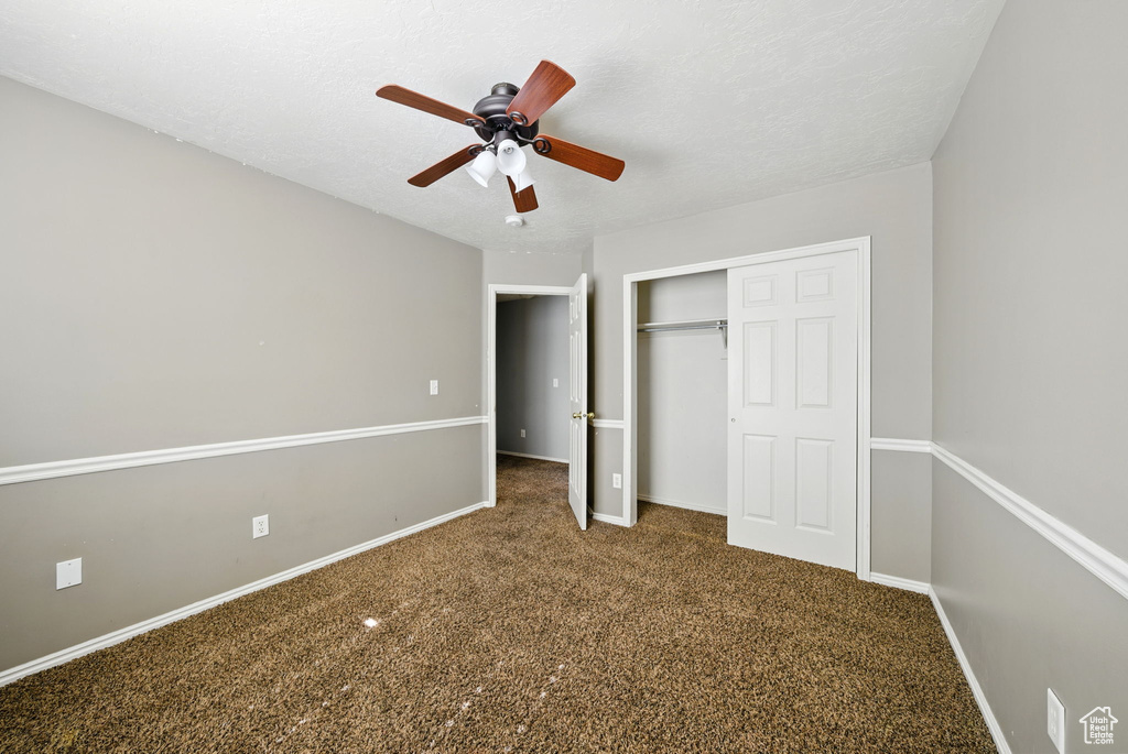 Unfurnished bedroom with a closet, carpet, baseboards, and ceiling fan
