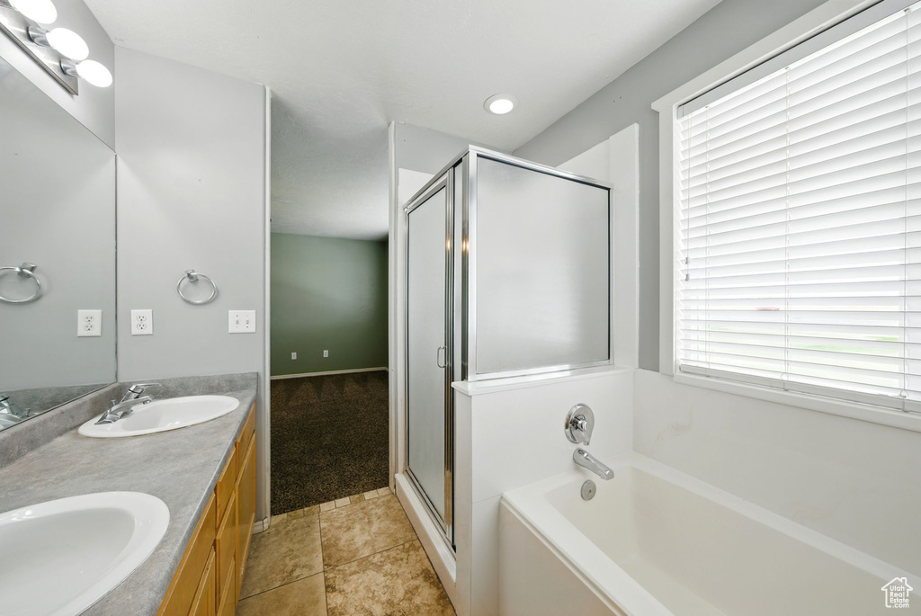 Full bathroom featuring a bath, double vanity, and a shower stall