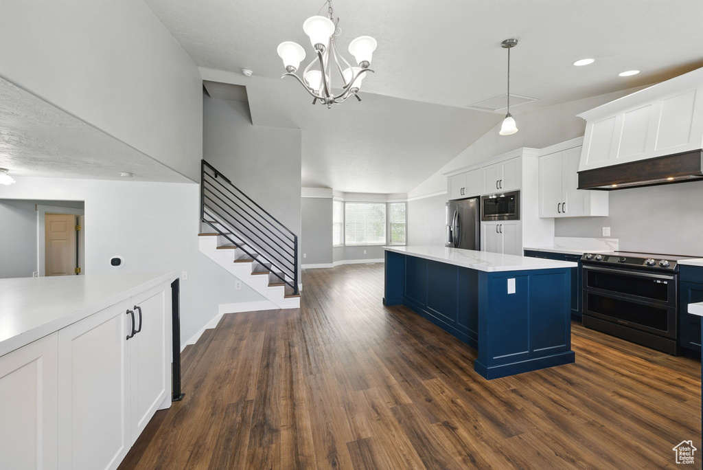 Kitchen featuring stainless steel appliances, lofted ceiling, light countertops, a kitchen island, and white cabinetry