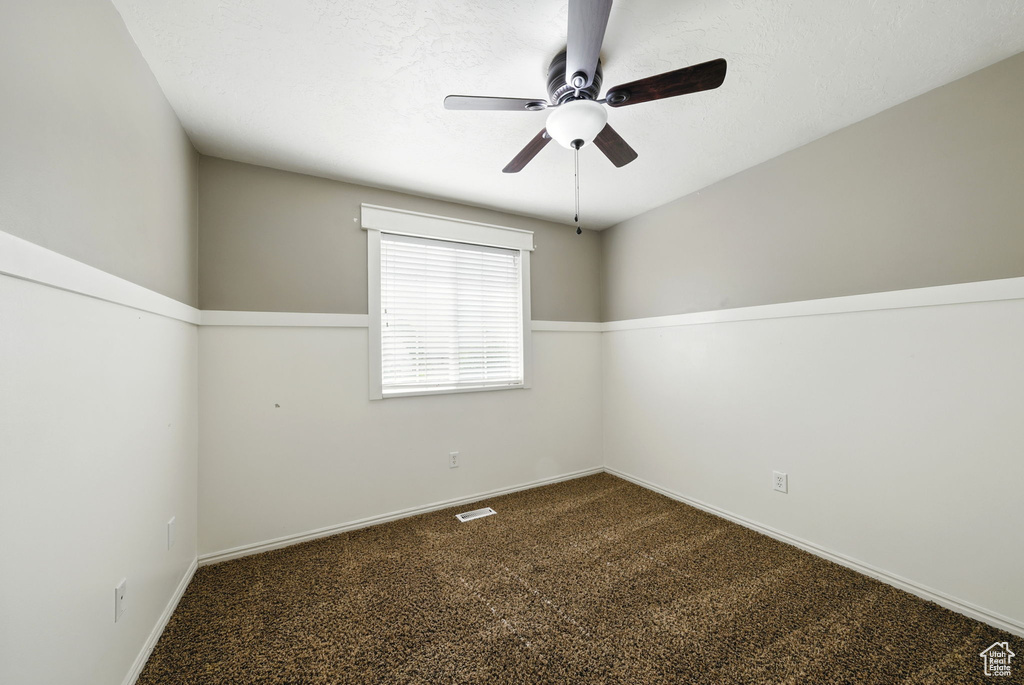 Carpeted empty room featuring ceiling fan and baseboards