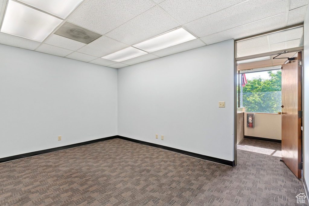 Carpeted empty room with baseboards and a paneled ceiling