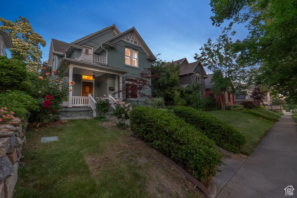 View of front of house with a balcony, a front lawn, and a porch