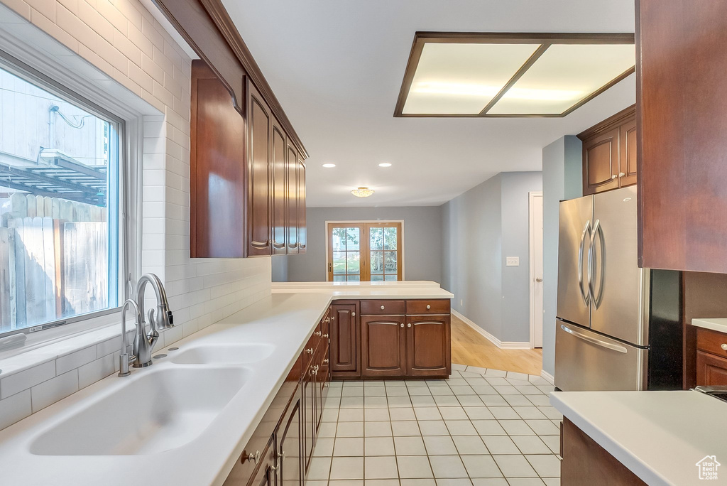 Kitchen with freestanding refrigerator, a sink, light countertops, light tile patterned floors, and a peninsula