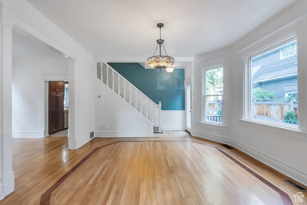 Empty room featuring light wood finished floors, stairs, and baseboards
