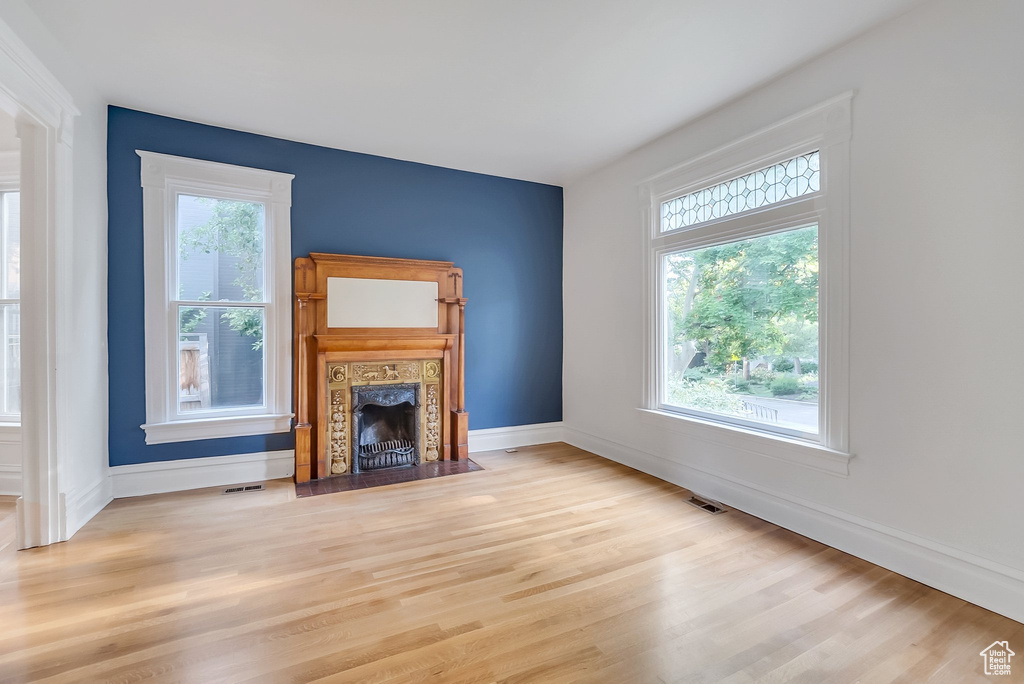 Unfurnished living room with light wood-style floors, a fireplace, and baseboards