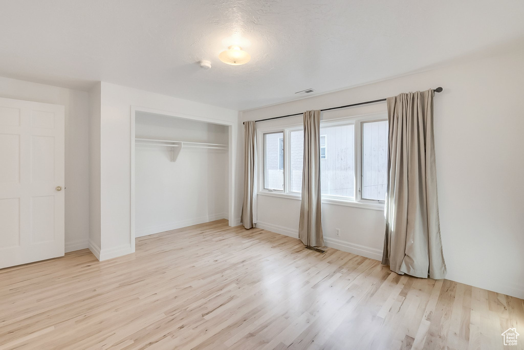Unfurnished bedroom featuring wood finished floors, a closet, and baseboards