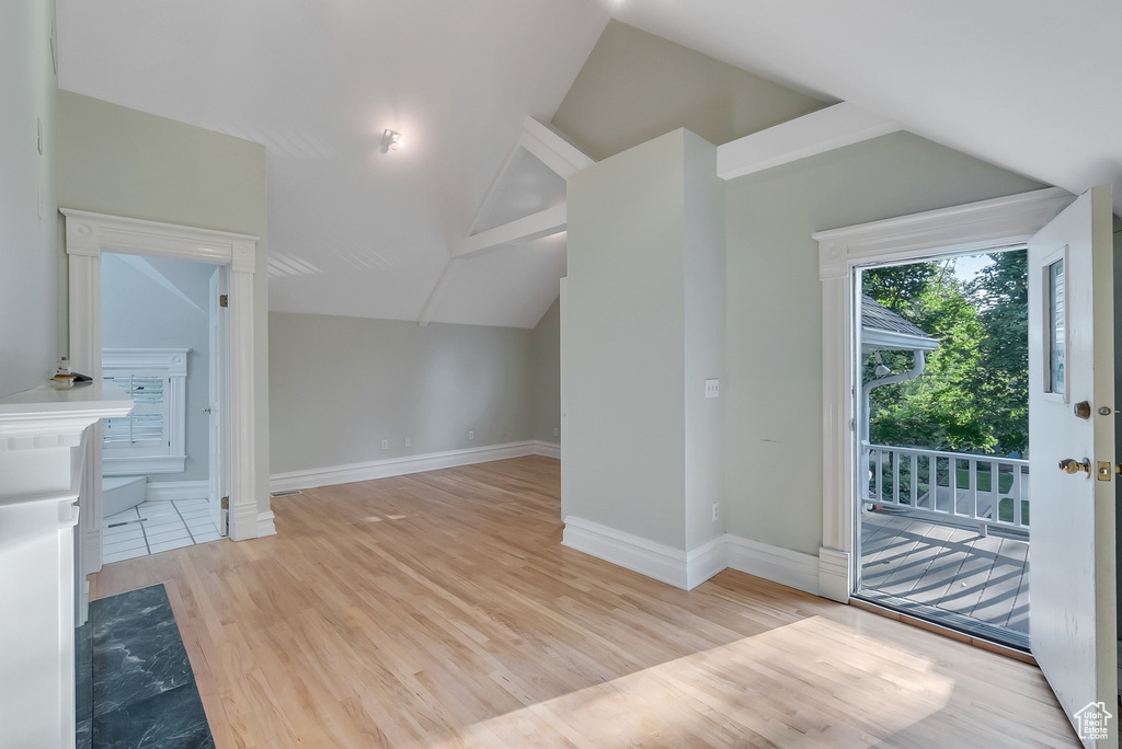 Additional living space with vaulted ceiling, light wood-style floors, and baseboards