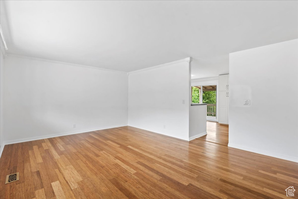 Spare room featuring light wood-style floors, baseboards, and ornamental molding