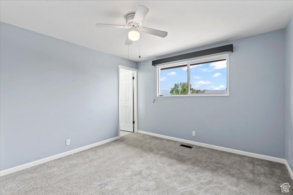 Carpeted empty room with baseboards and a ceiling fan