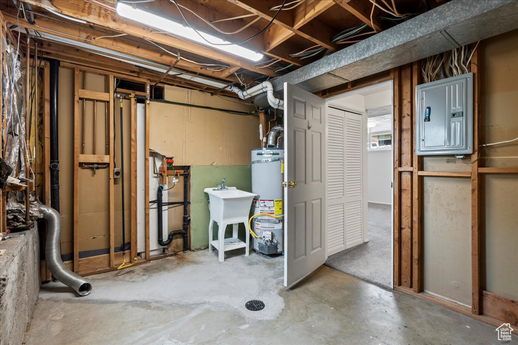 Unfinished below grade area with secured water heater, electric panel, and a sink