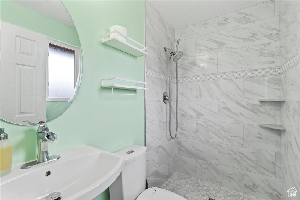 Bathroom with a sink, a tile shower, and toilet