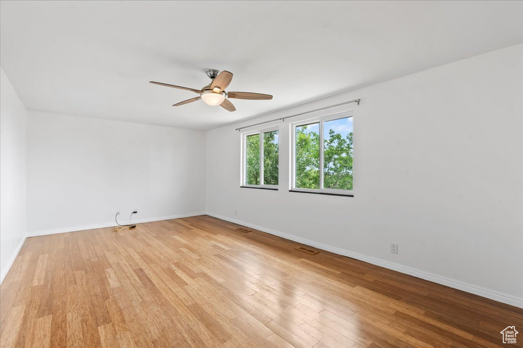 Unfurnished room featuring light wood-type flooring, baseboards, and a ceiling fan