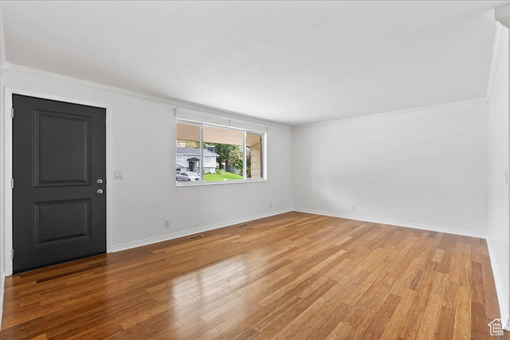 Unfurnished room with ornamental molding, wood finished floors, and baseboards