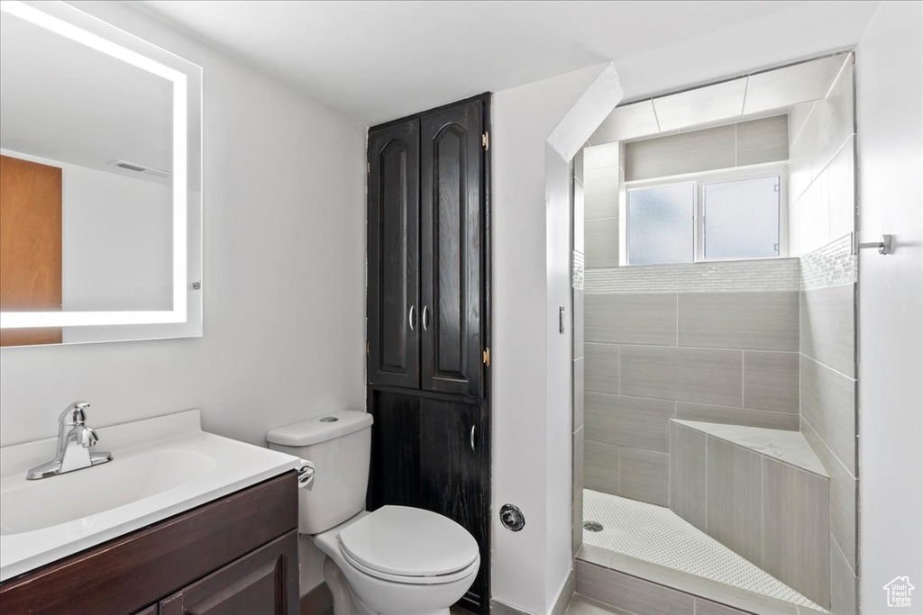 Bathroom featuring vanity, tiled shower, and toilet