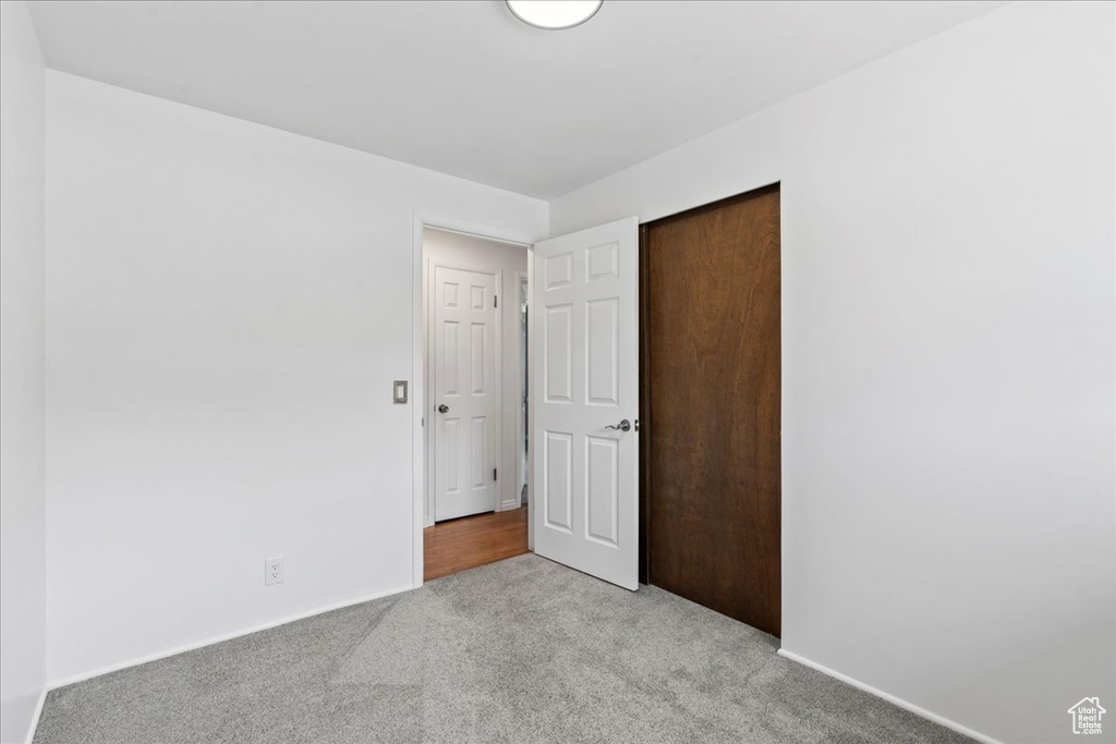Unfurnished bedroom featuring light colored carpet, a closet, and baseboards