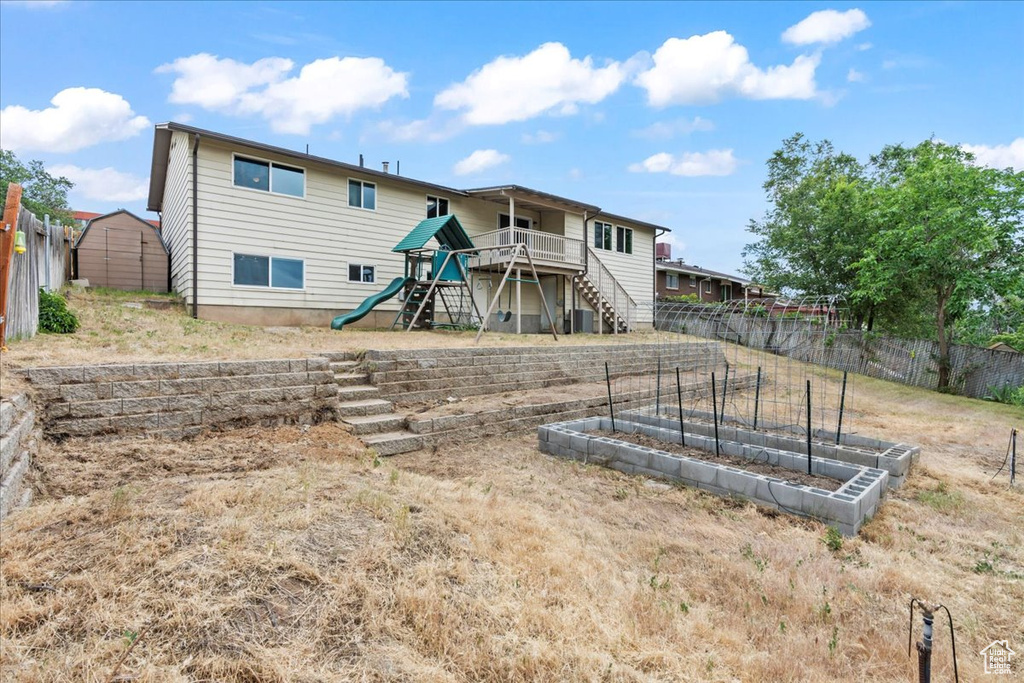 Rear view of house with a garden, a playground, and stairs