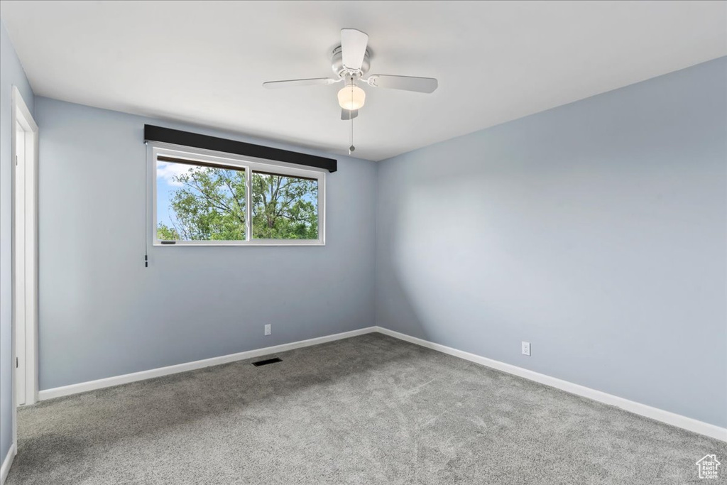 Carpeted spare room with a ceiling fan and baseboards