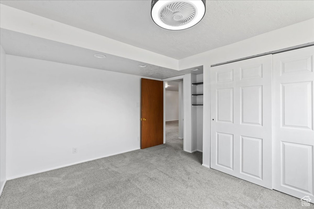 Unfurnished bedroom featuring carpet floors, a closet, a textured ceiling, and baseboards