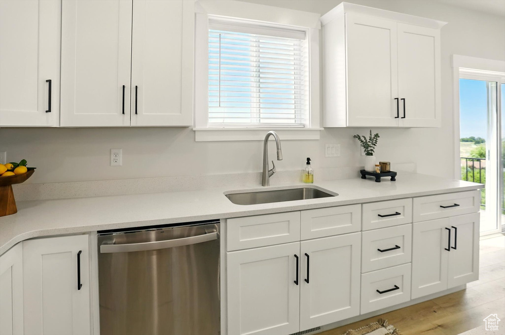 Kitchen featuring dishwasher, a sink, white cabinetry, and light countertops