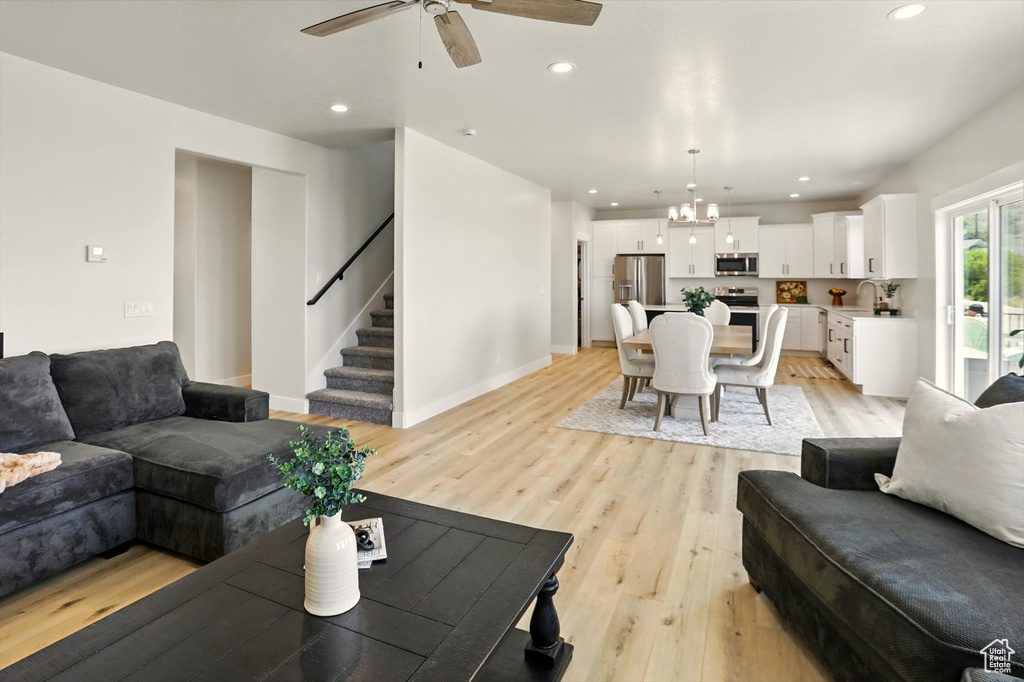 Living area featuring a ceiling fan, light wood-style flooring, stairs, recessed lighting, and baseboards