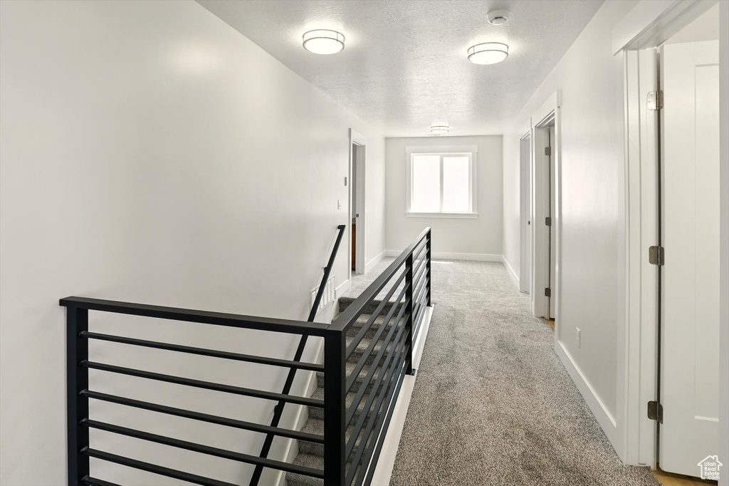 Corridor featuring light carpet, baseboards, and an upstairs landing