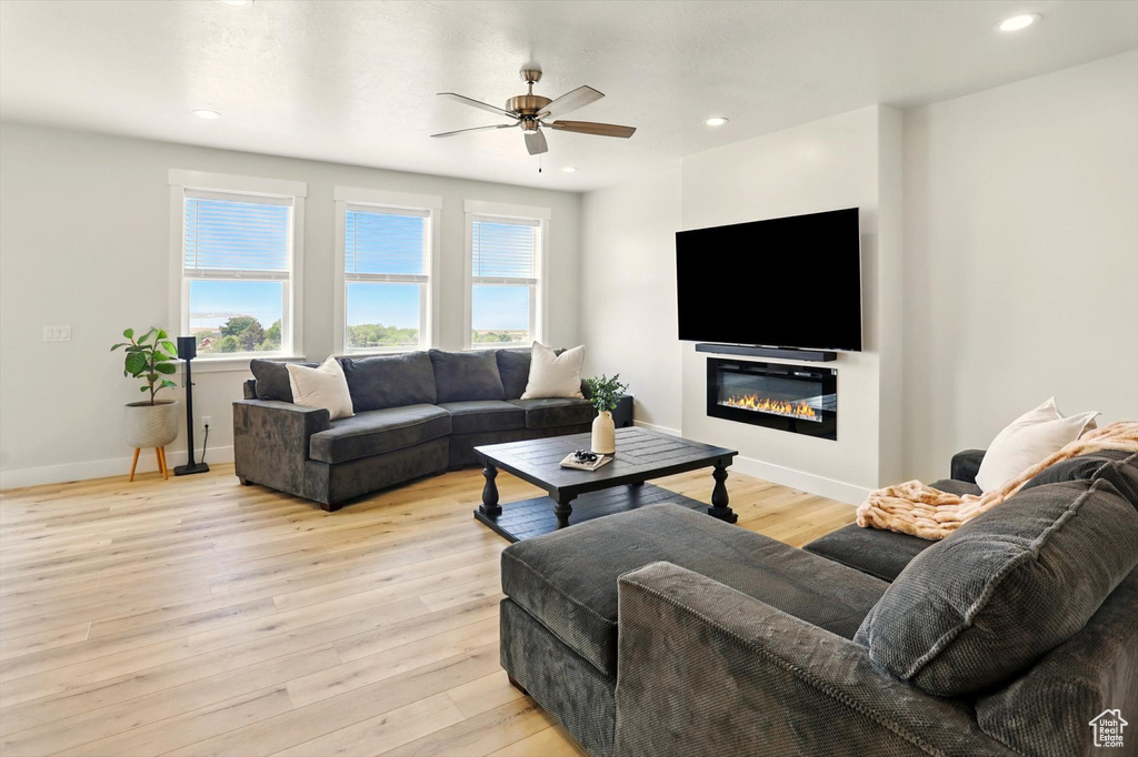 Living area featuring healthy amount of natural light, ceiling fan, baseboards, light wood-type flooring, and recessed lighting