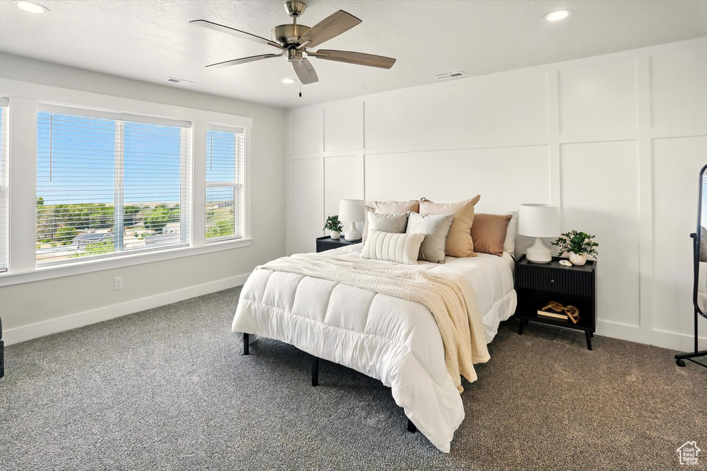 Bedroom featuring dark carpet, multiple windows, recessed lighting, a decorative wall, and baseboards