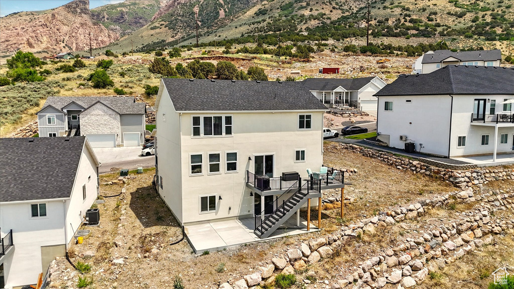Back of house with central AC unit, a patio area, a residential view, and stucco siding