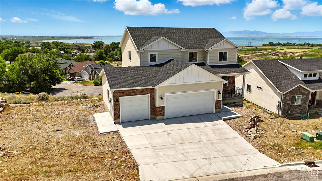 View of front facade featuring board and batten siding, an attached garage, a water and mountain view, and brick siding