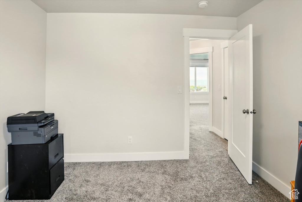 Spare room featuring carpet flooring, baseboards, and a smoke detector
