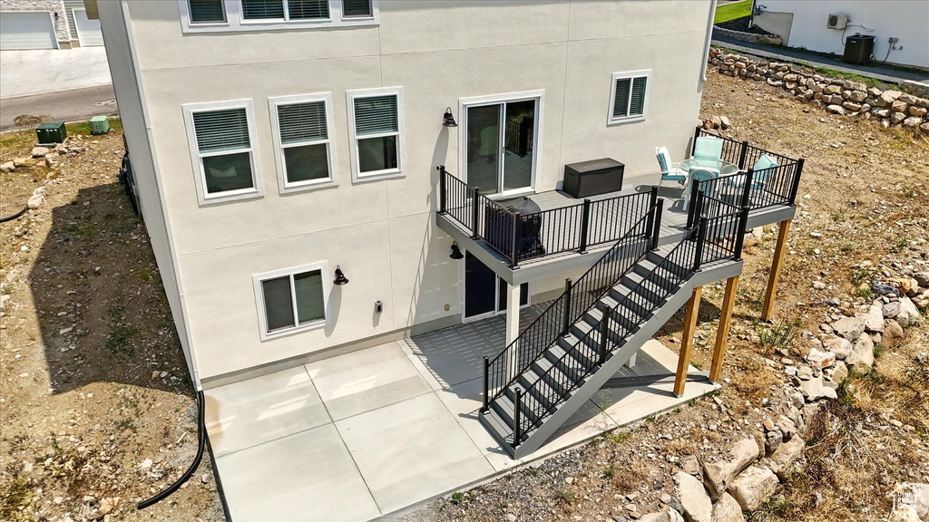 Back of house with stairway, a patio area, a deck, stucco siding, and central air condition unit