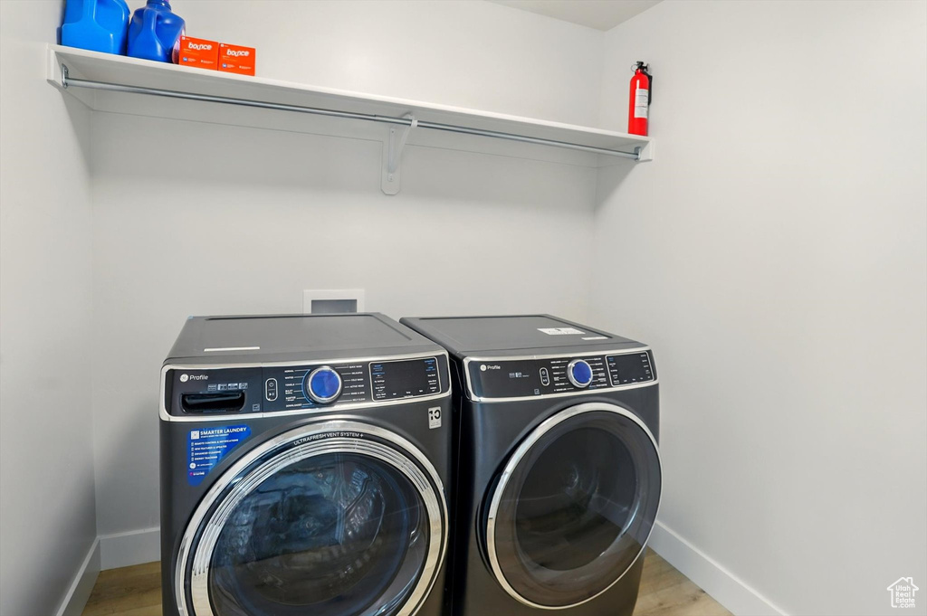 Laundry area with washer and dryer, baseboards, and wood finished floors