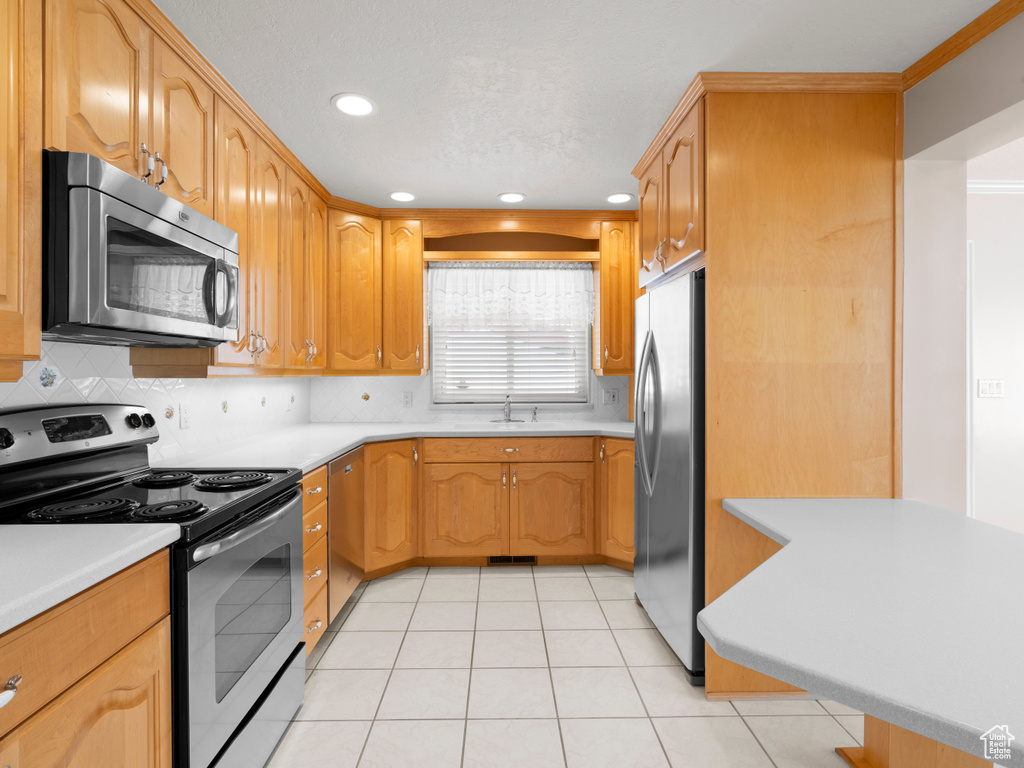 Kitchen with appliances with stainless steel finishes, recessed lighting, backsplash, light countertops, and a sink