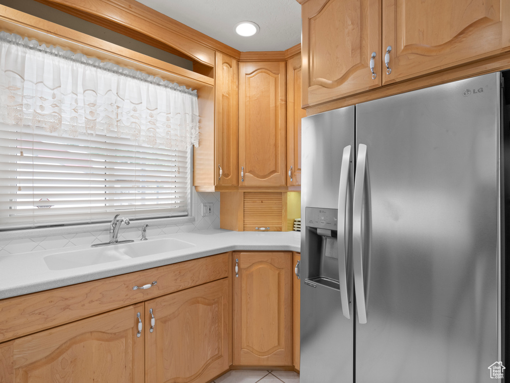 Kitchen featuring stainless steel refrigerator with ice dispenser, a sink, and light countertops