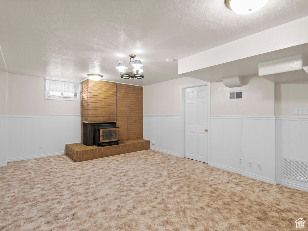 Below grade area featuring a wainscoted wall, carpet floors, a textured ceiling, and a chandelier