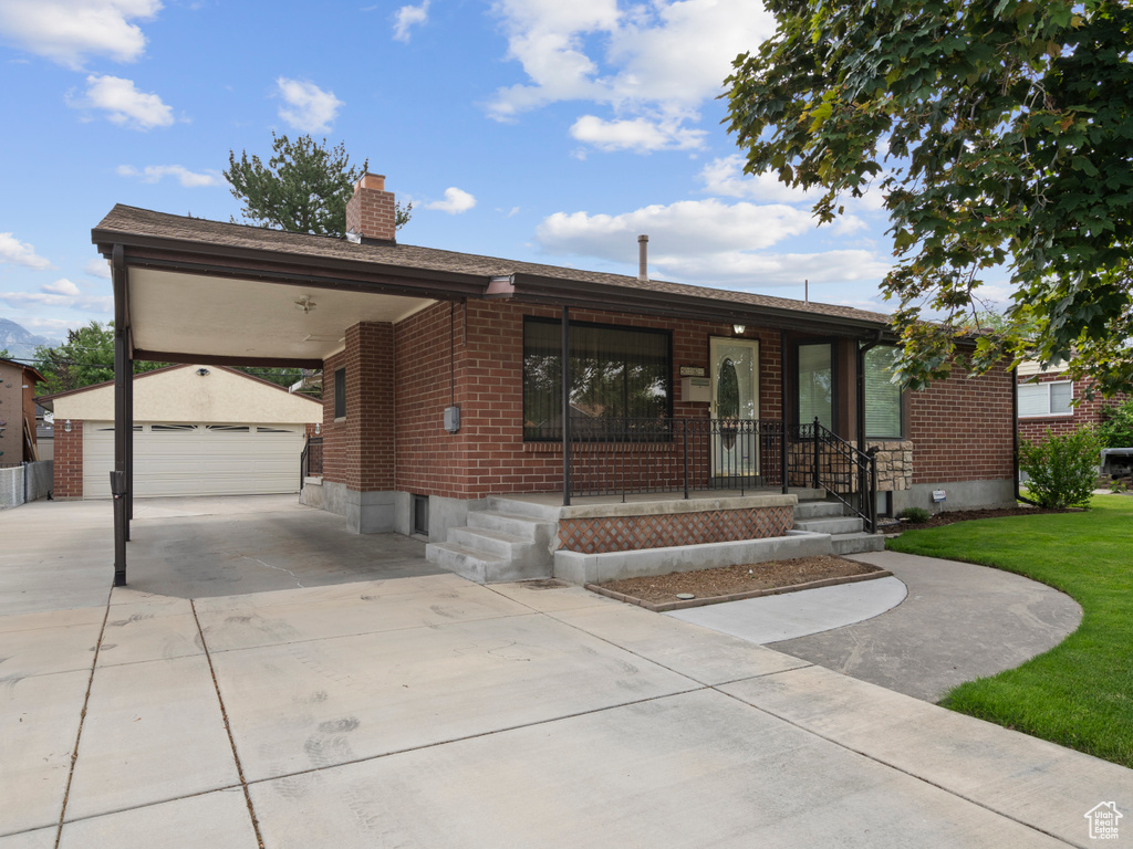 Ranch-style home with an outbuilding, brick siding, a chimney, a front lawn, and a garage