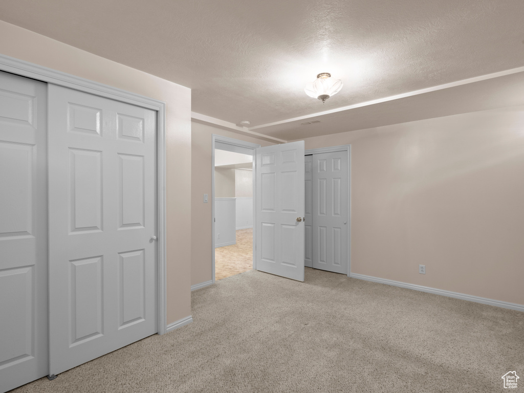 Unfurnished bedroom featuring baseboards, carpet, and a textured ceiling
