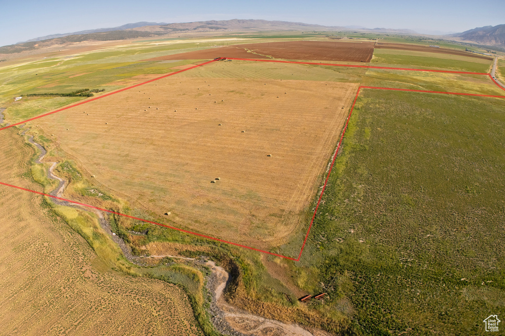 Aerial view of sparsely populated area with property parcel outlined, mountains, and large plots for crops