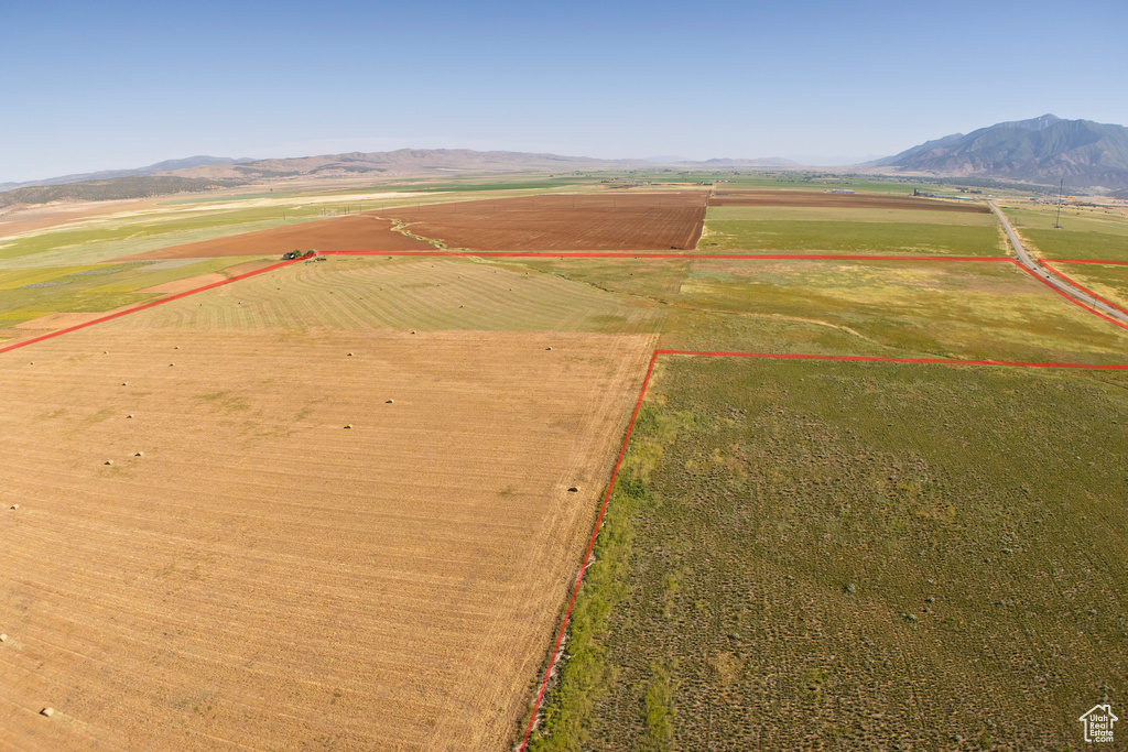 Aerial view of sparsely populated area with property parcel outlined, a mountainous background, and farmland