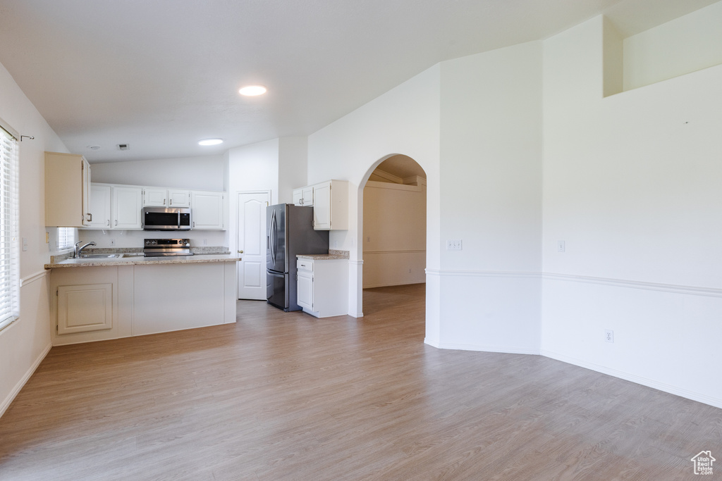 Kitchen with stainless steel appliances, arched walkways, open floor plan, a peninsula, and recessed lighting