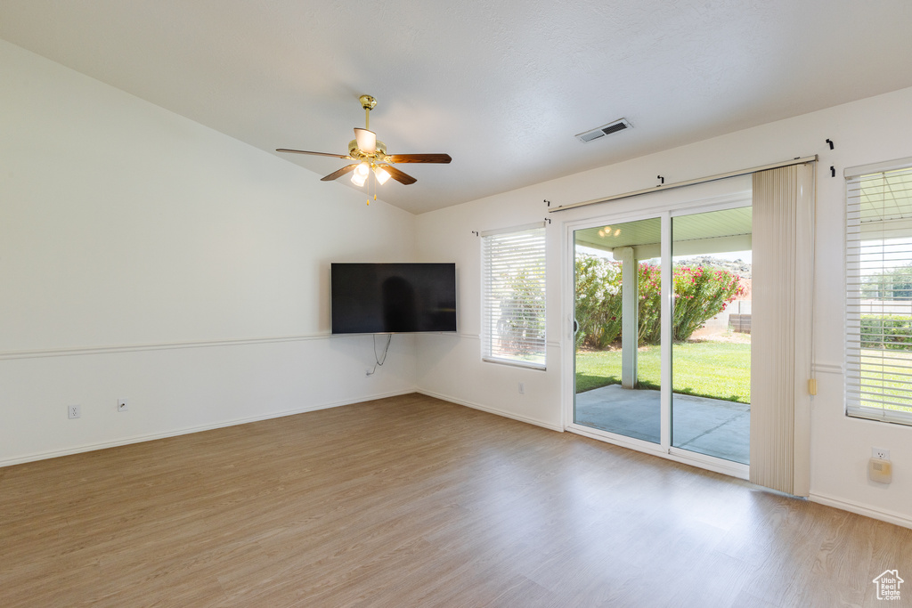 Unfurnished living room with light wood-style flooring, ceiling fan, baseboards, plenty of natural light, and vaulted ceiling