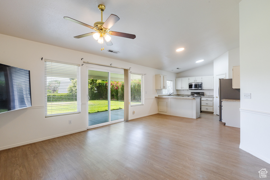 Unfurnished living room featuring lofted ceiling, light wood finished floors, baseboards, a ceiling fan, and recessed lighting