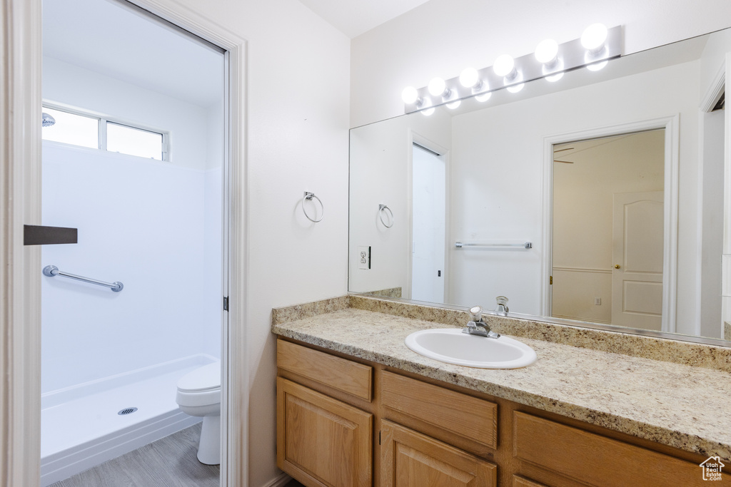 Bathroom featuring toilet, vanity, and a shower