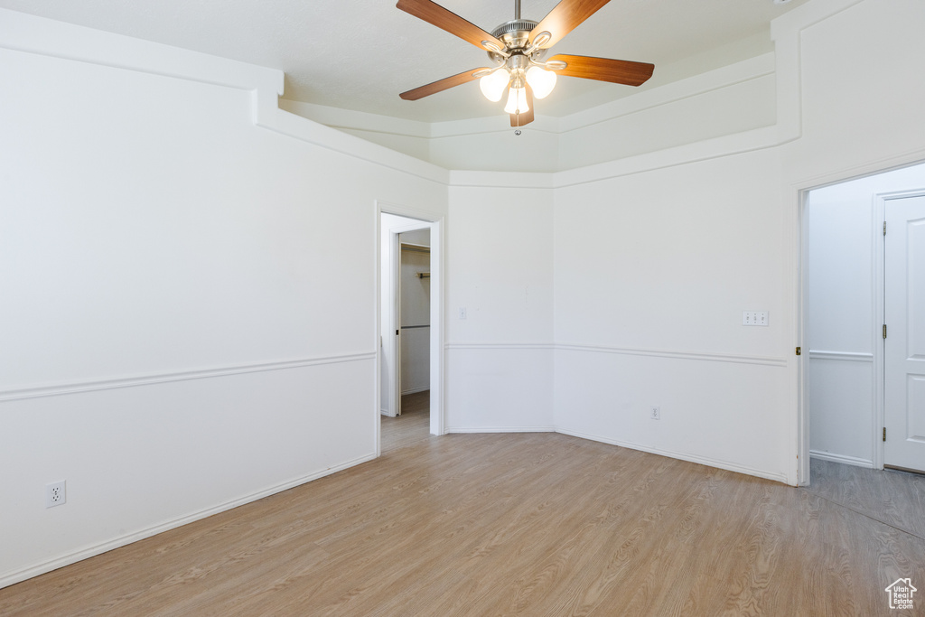 Unfurnished room featuring light wood-type flooring, ceiling fan, and baseboards