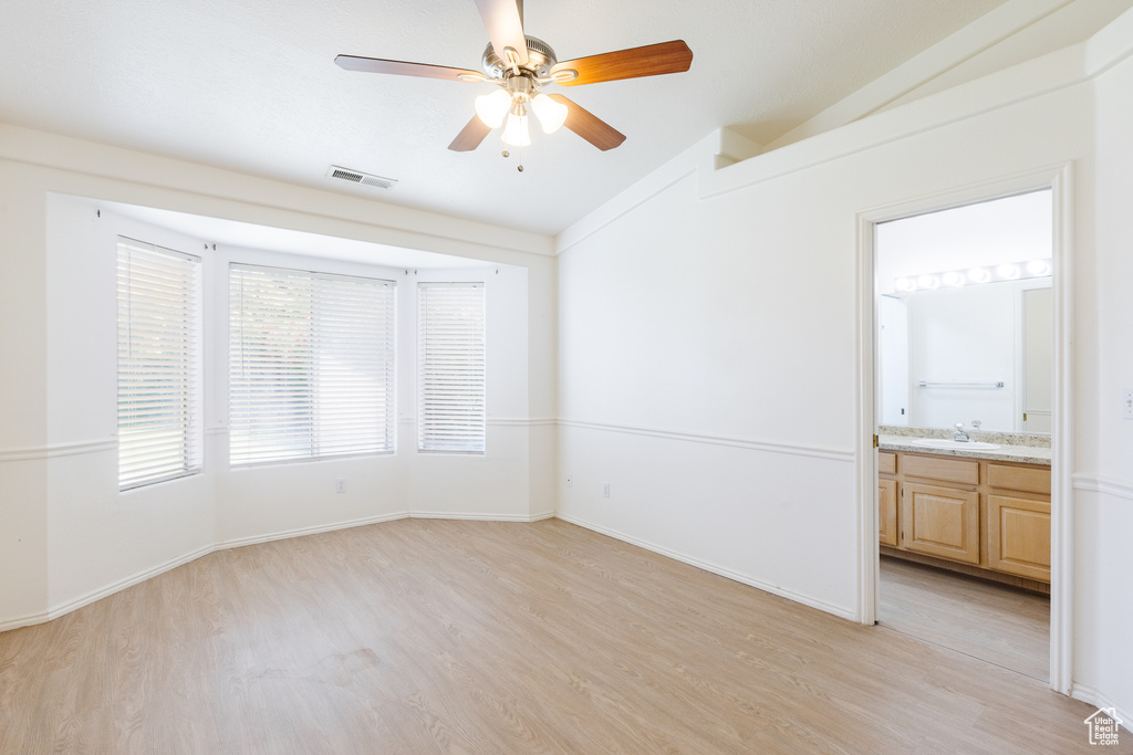 Unfurnished room with lofted ceiling, light wood-style floors, ceiling fan, a sink, and baseboards