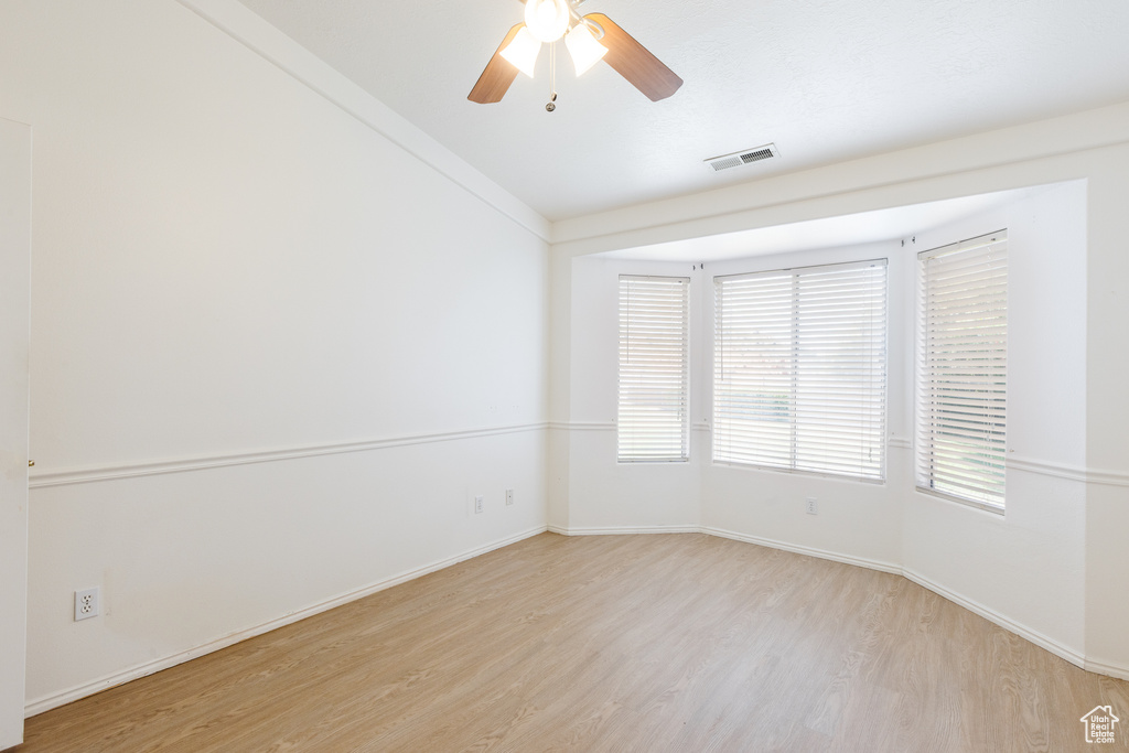 Empty room with light wood-style flooring, baseboards, and a ceiling fan