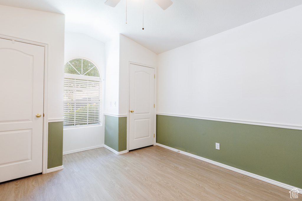 Unfurnished room featuring wood finished floors, lofted ceiling, a ceiling fan, and baseboards
