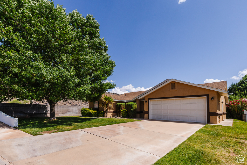 Ranch-style home featuring stucco siding, concrete driveway, a front lawn, and an attached garage