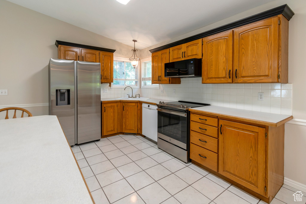 Kitchen with stainless steel appliances, light countertops, backsplash, and brown cabinets
